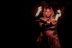 Fire torch performer holding two flames; metal grips with light fabric wraps