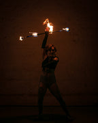 Fire hoop with burning wicks on a ring, performer holding prop overhead.