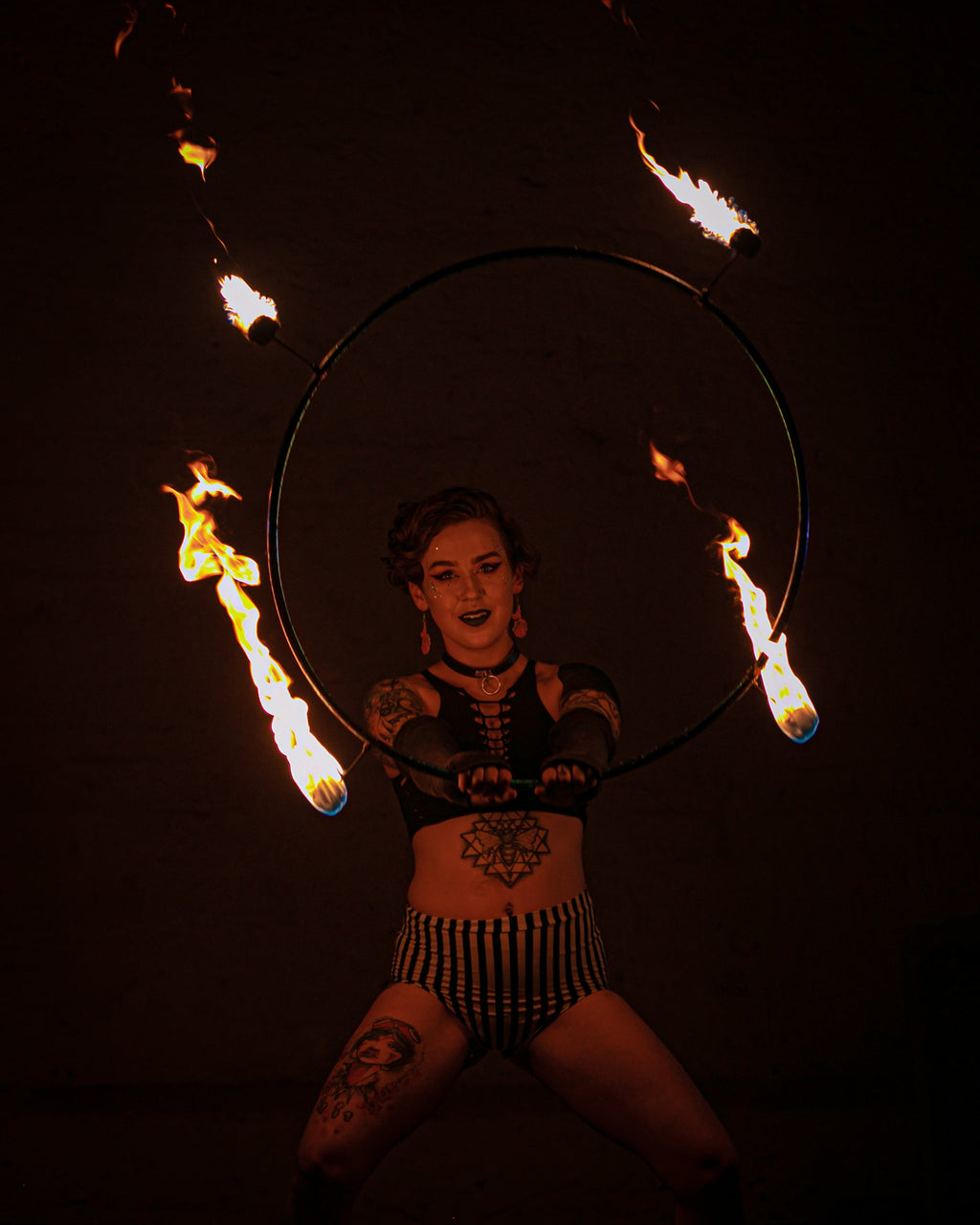 Fire hoop ring with burning wicks, held by performer.