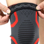 Black knee sleeve detail with red panel accents, textured grip fabric, and support ridges.