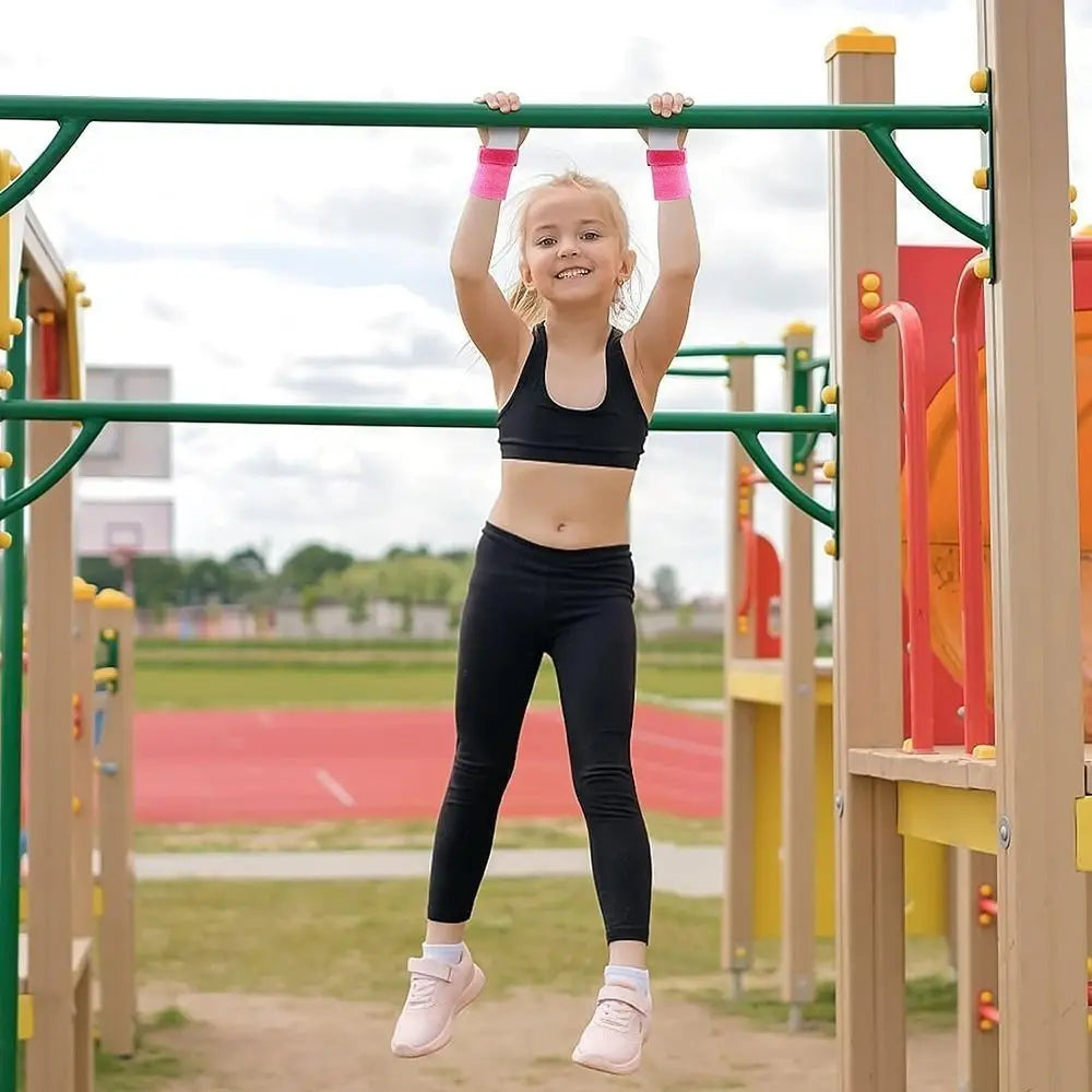 Child wearing pink aerial grip wristbands while hanging from an outdoor play bar